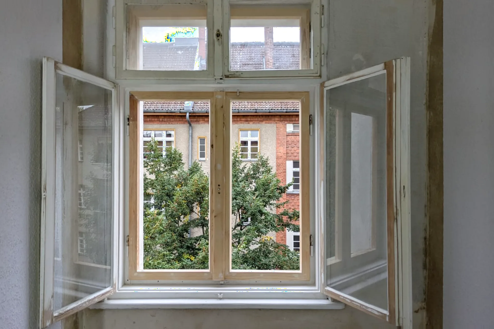 Geöffnetes, aufgearbeitetes Holzfenster mit Blick ins Grüne