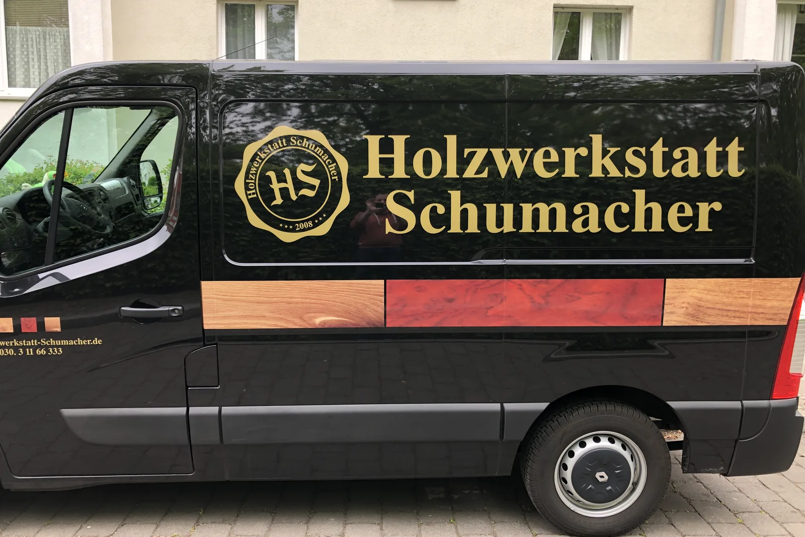 Schwarzer Firmentransporter mit Logo der Holzwerkstatt Schumacher