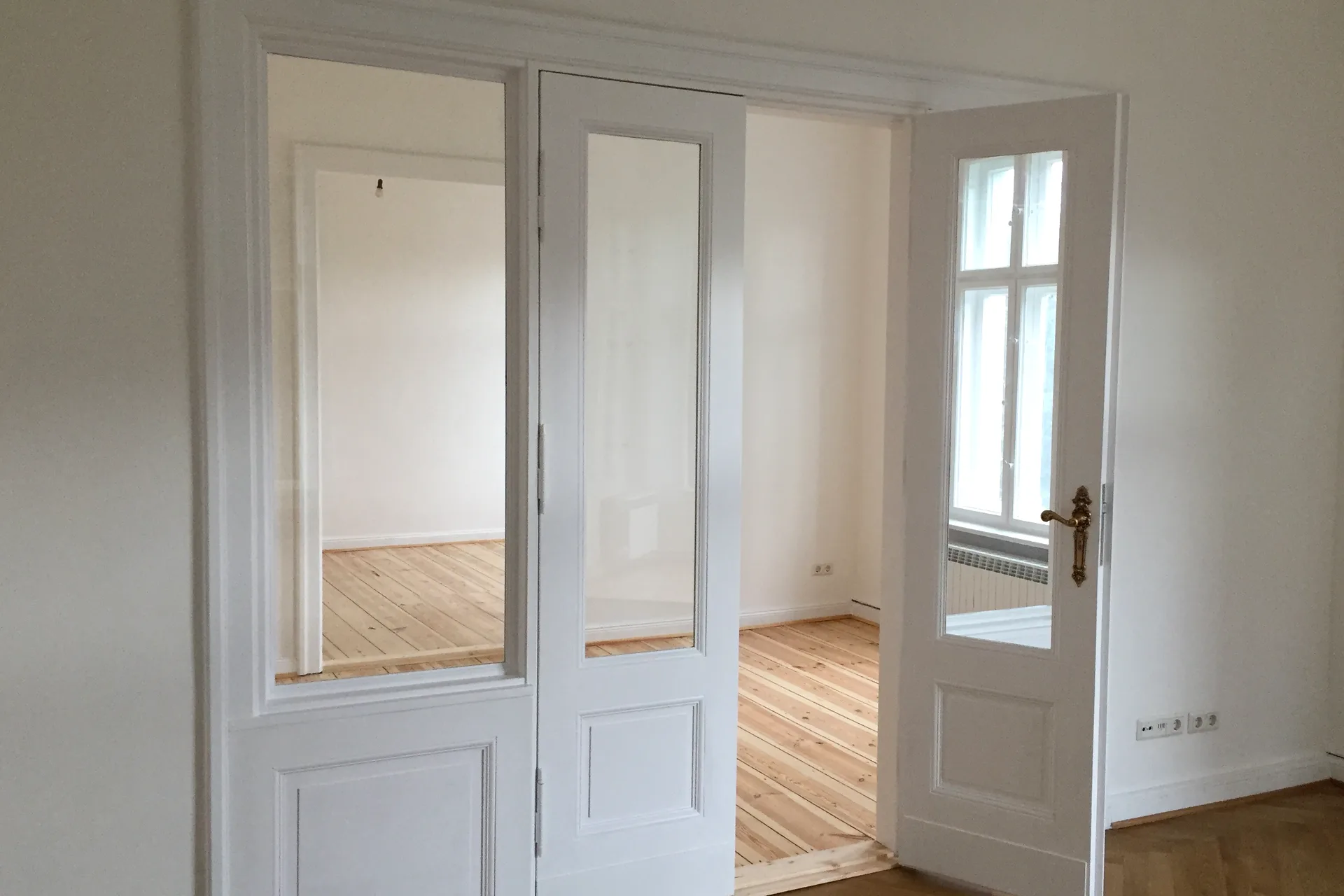 Weiße Altbau-Flügeltür mit Glaseinsatz und Messinggriff