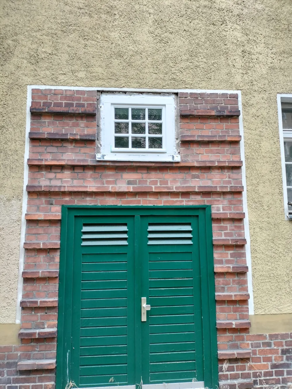 Grüne Klapplädentür an einer Backsteinfassade